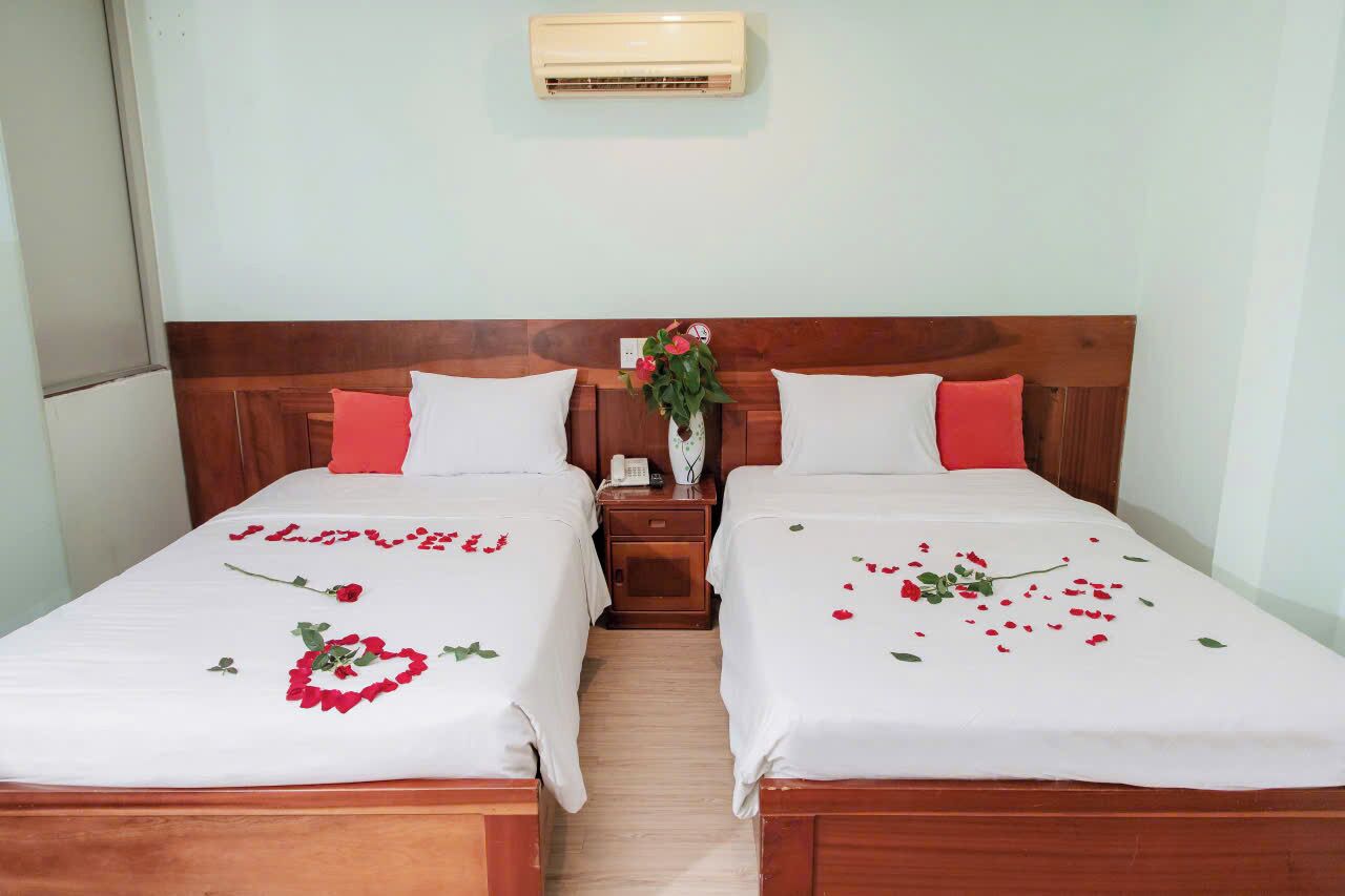 A double bed with white bedding and red rose decorations.