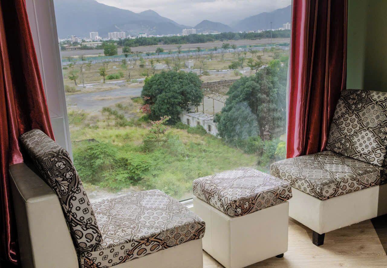 A room with two patterned sofas facing a large window.