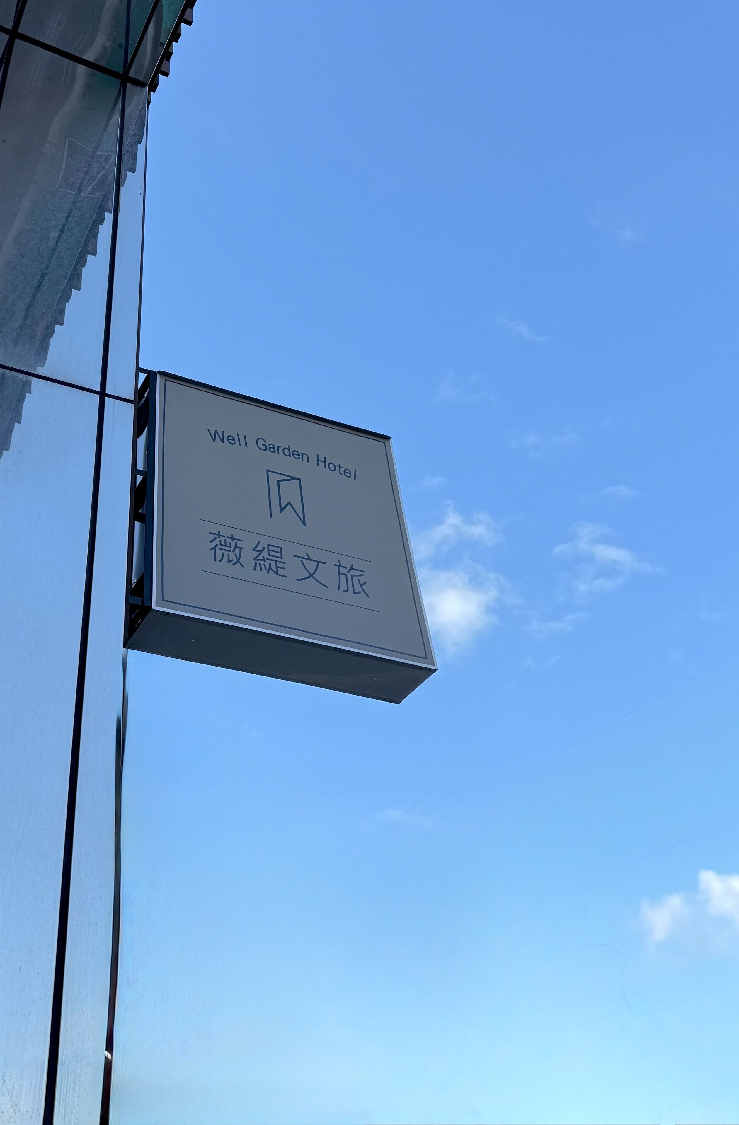 A sign for the Well Garden Hotel with a clear blue sky in the background.