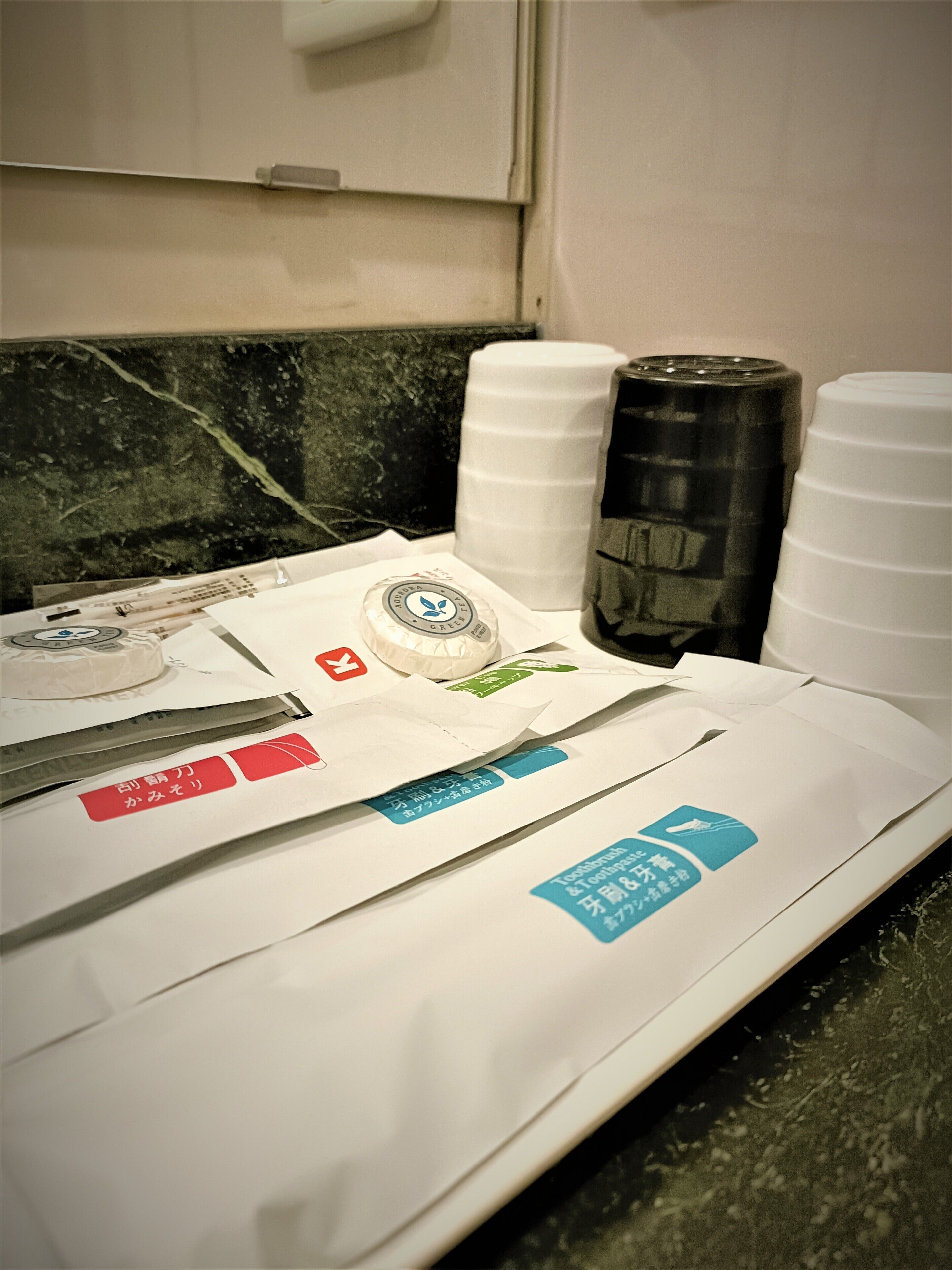 A table with various items including a white container, a black container, and some papers with text.