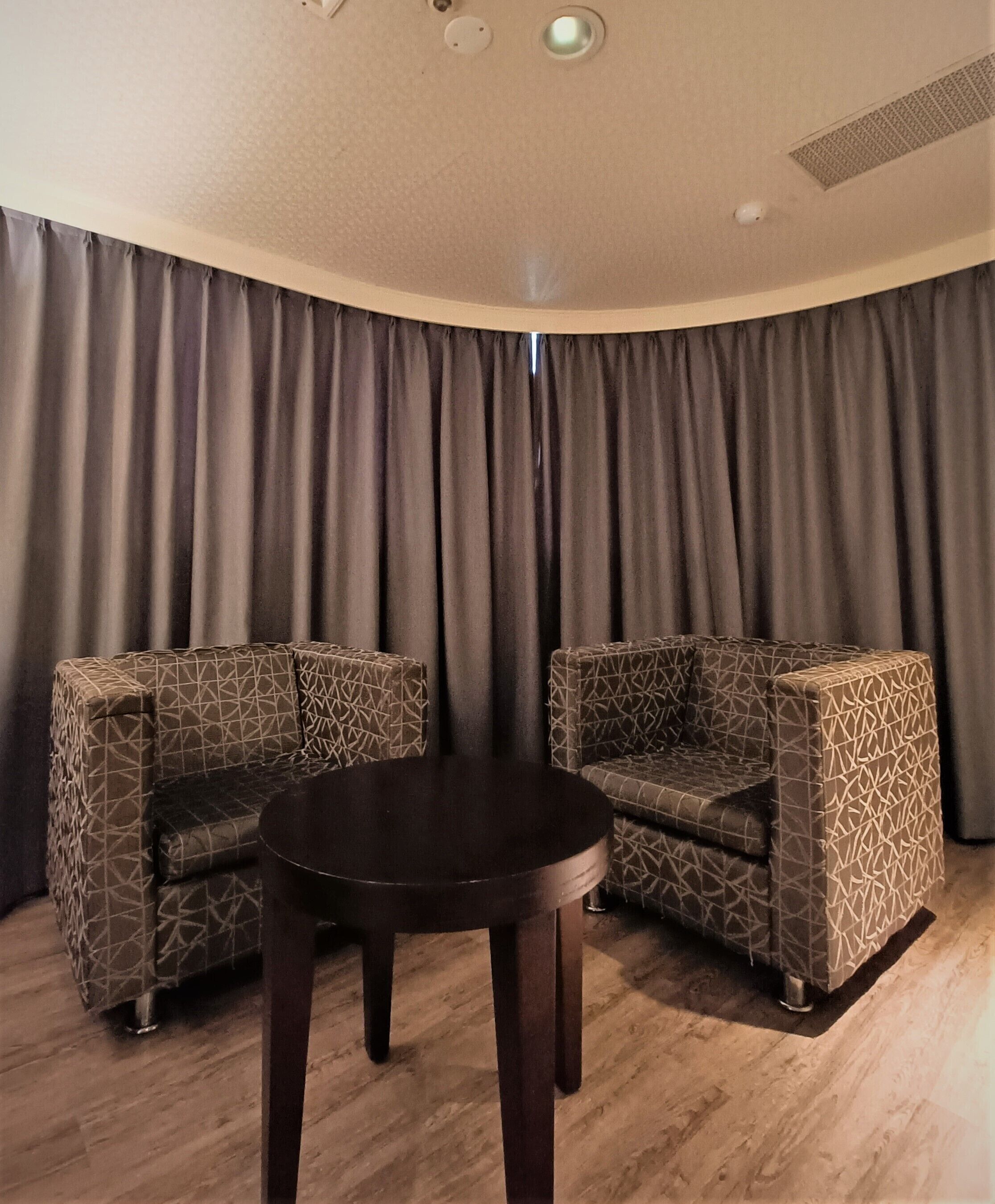 A room with two patterned sofas and a round table.