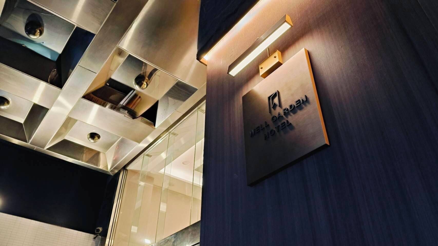 A modern interior with a metallic ceiling, a wooden wall with a sign, and a glass partition.
