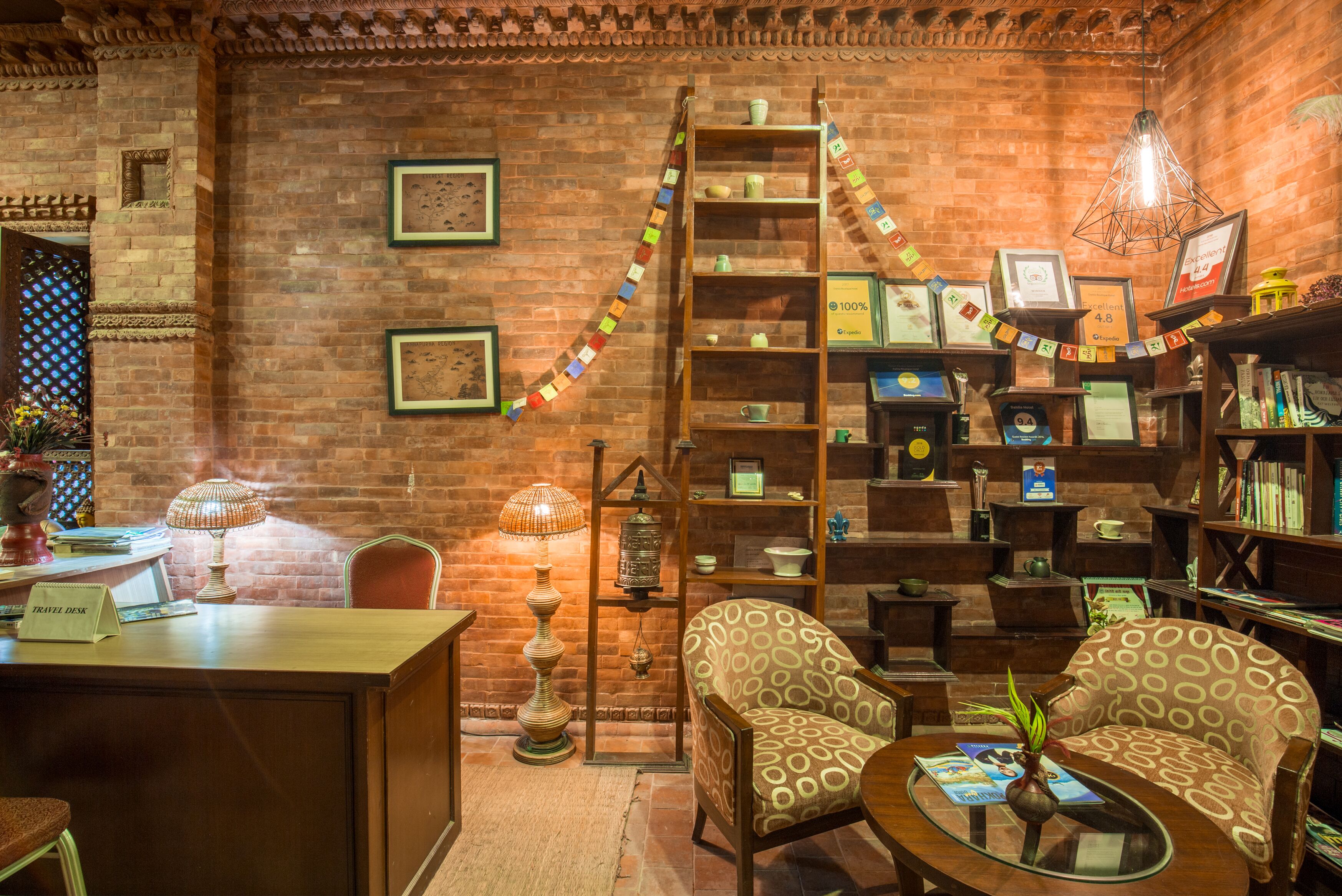 A cozy, rustic room with a wooden desk, patterned chairs, a bookshelf, and a ladder.