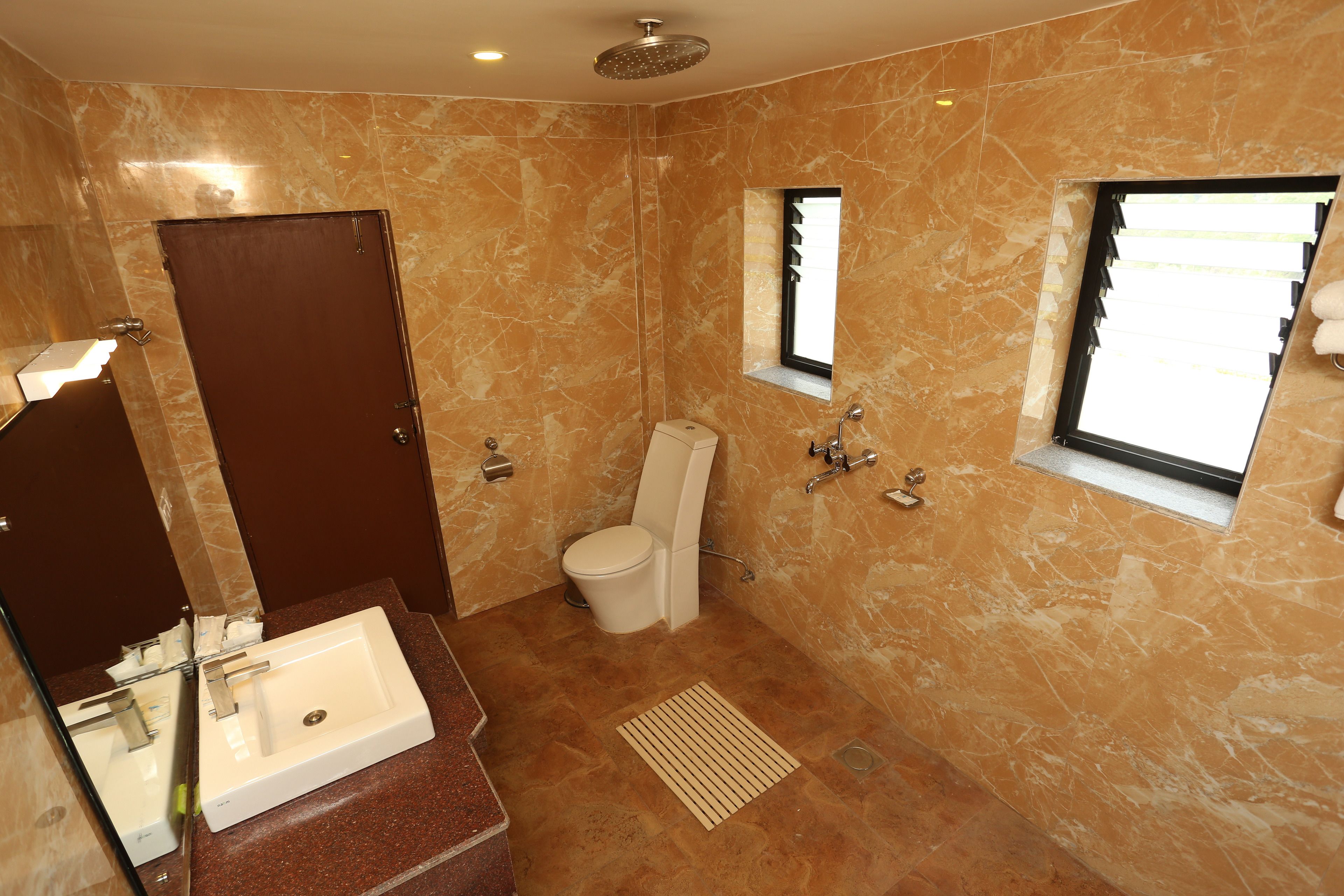 A bathroom with a marble floor, a sink, a toilet, and a shower.