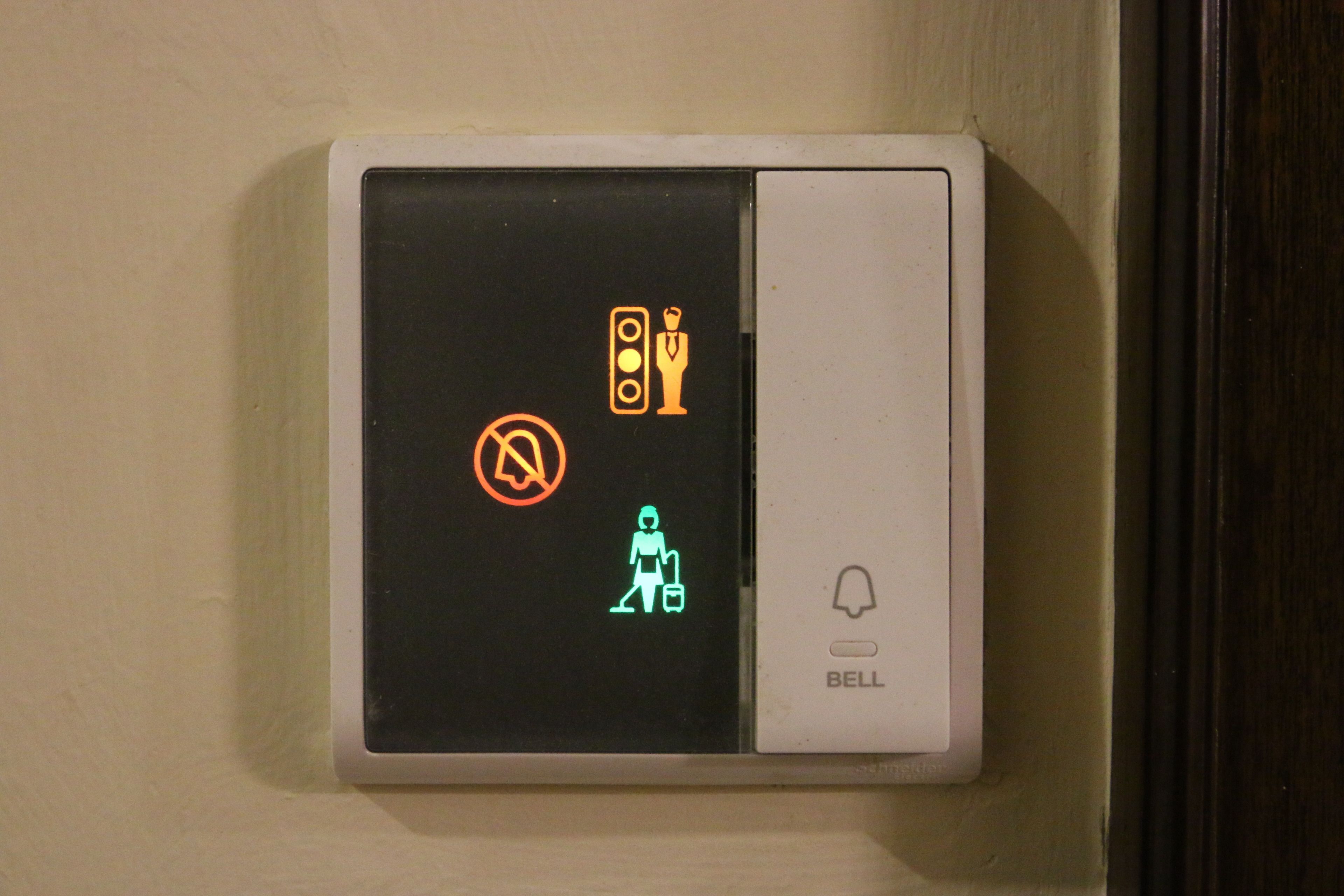A wall-mounted intercom system with a no-entry sign, a pedestrian crossing signal, and a bell button.
