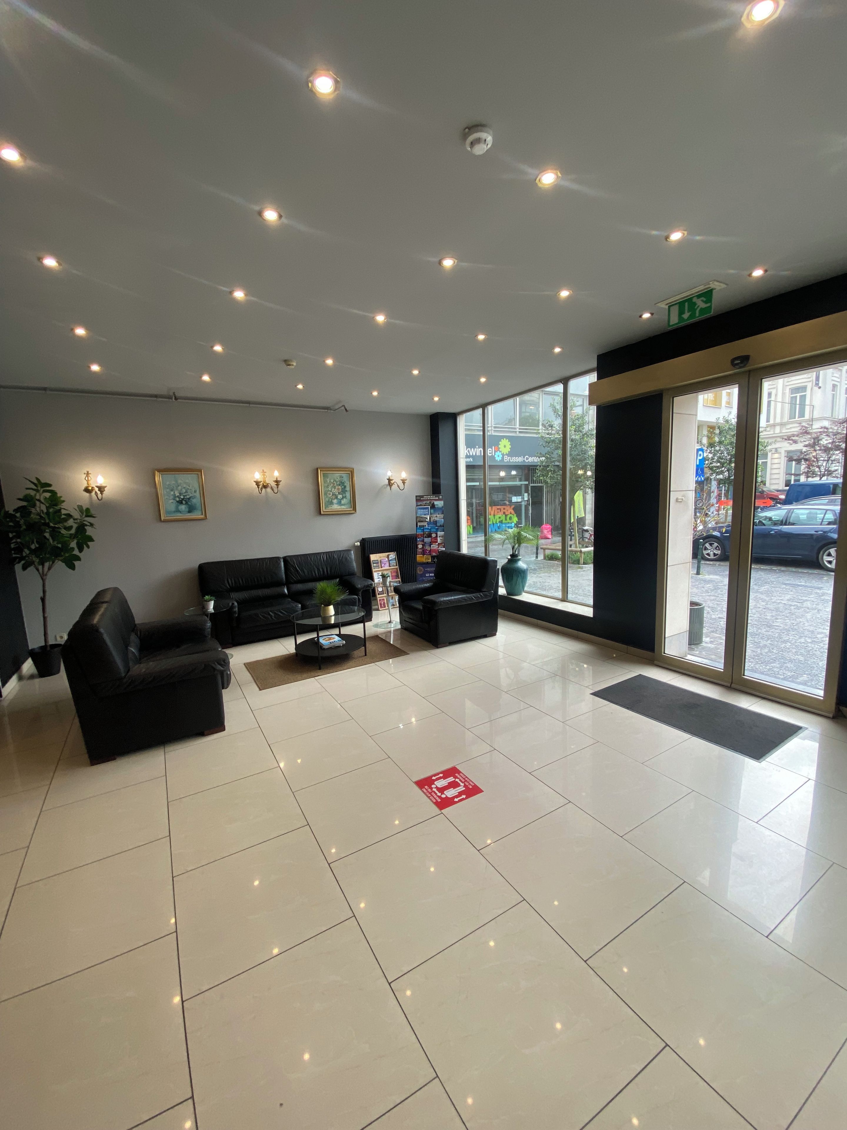 A spacious lobby with a black sofa set, a coffee table, and a potted plant.