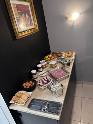 A buffet table with various food items and condiments. - Hotel Windsor (Brussels)