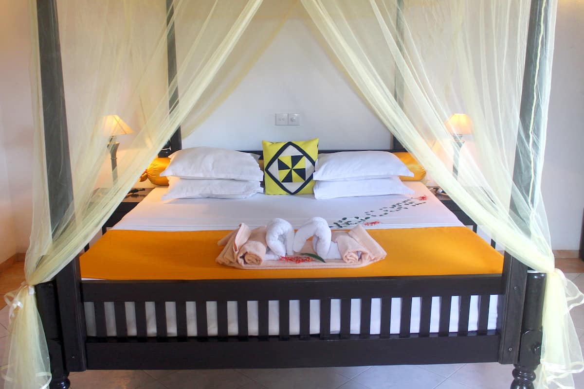 A bed with a canopy, white pillows, and a yellow blanket.