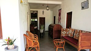 Amplia sala de estar con un sofá, dos sillones de mimbre, una mesita y una planta en maceta.