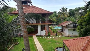 Una zona residencial con piscina, un pequeño estanque y un patio con mobiliario de exterior.