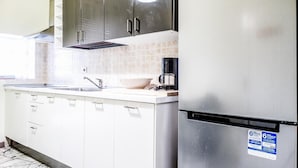 A modern kitchen with stainless steel appliances, white cabinetry, and a tiled backsplash. - Iris Florentina (Florence)