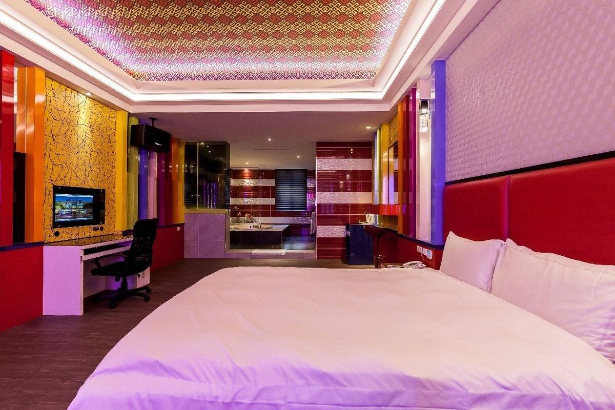 A modern hotel room with a large bed, a desk with a computer, and a TV.