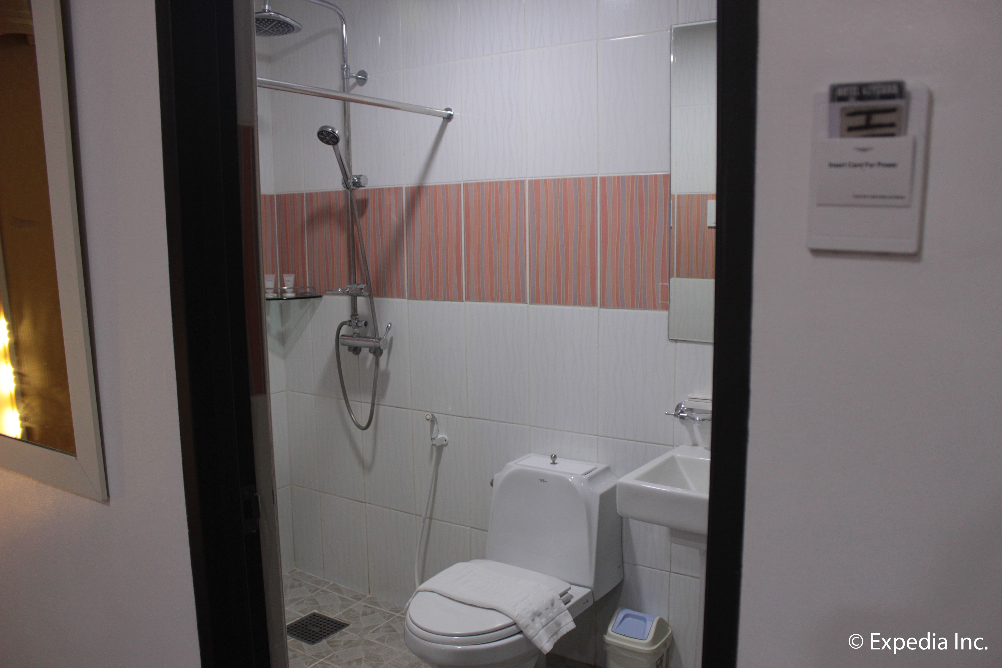A compact hotel bathroom with a shower, toilet, and sink.