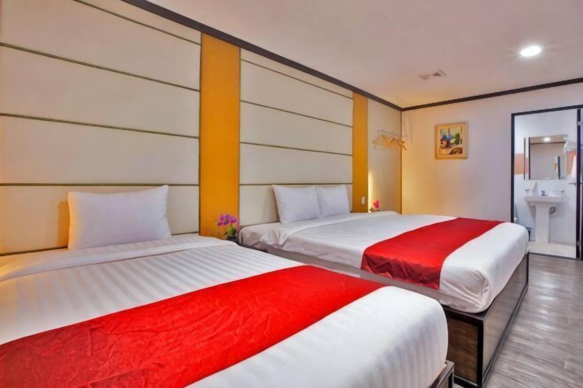 Habitación de hotel con dos camas, baño y una pequeña zona de estar.