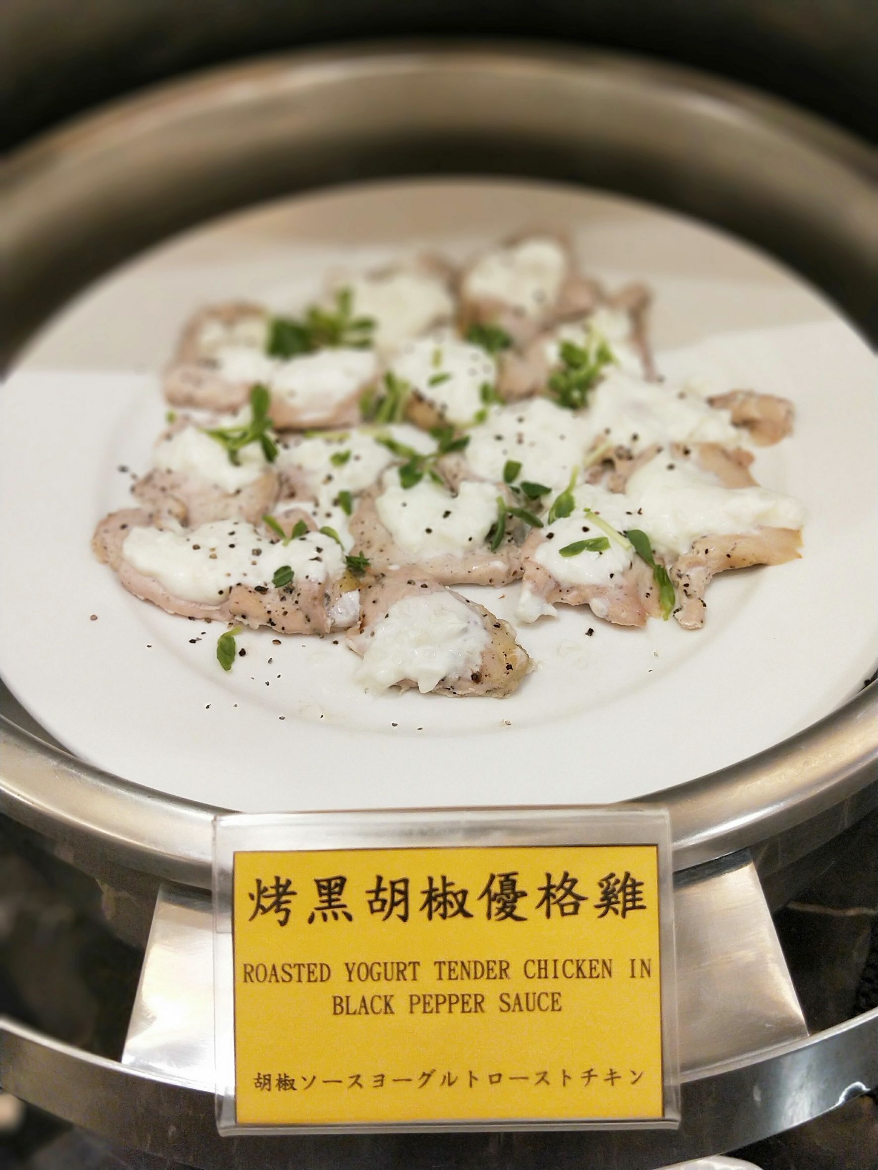 A dish of roasted yogurt tender chicken in black pepper sauce, garnished with herbs.