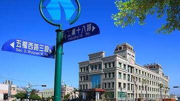 A street sign with directions to "Wuquan W. Rd." and "Industry 18 Rd." in front of a building with a classic architectural style.