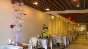 Un comedor con mesas dispuestas para el servicio, un arreglo floral decorativo y una escultura de vidrio original.