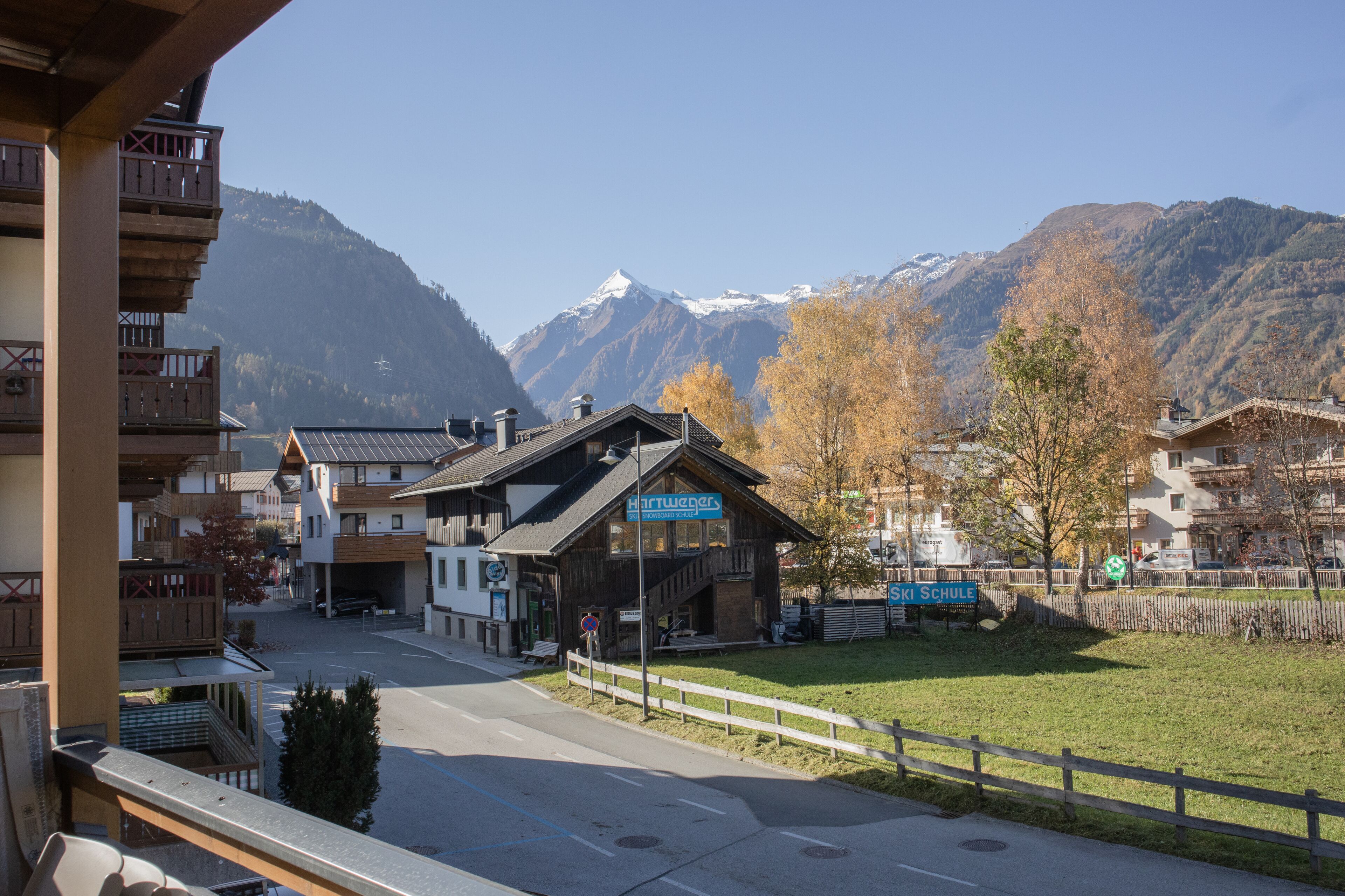 A mountain town with a wooden building labeled "Hartwanger" and a sign for "Ski Schule".
