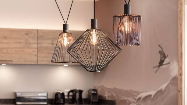 A modern kitchen with pendant lights, a wooden backsplash, and a mountain mural on the wall. - AvenidA Style Appartments by Alpin Rentals -incl Summercard (Kaprun)