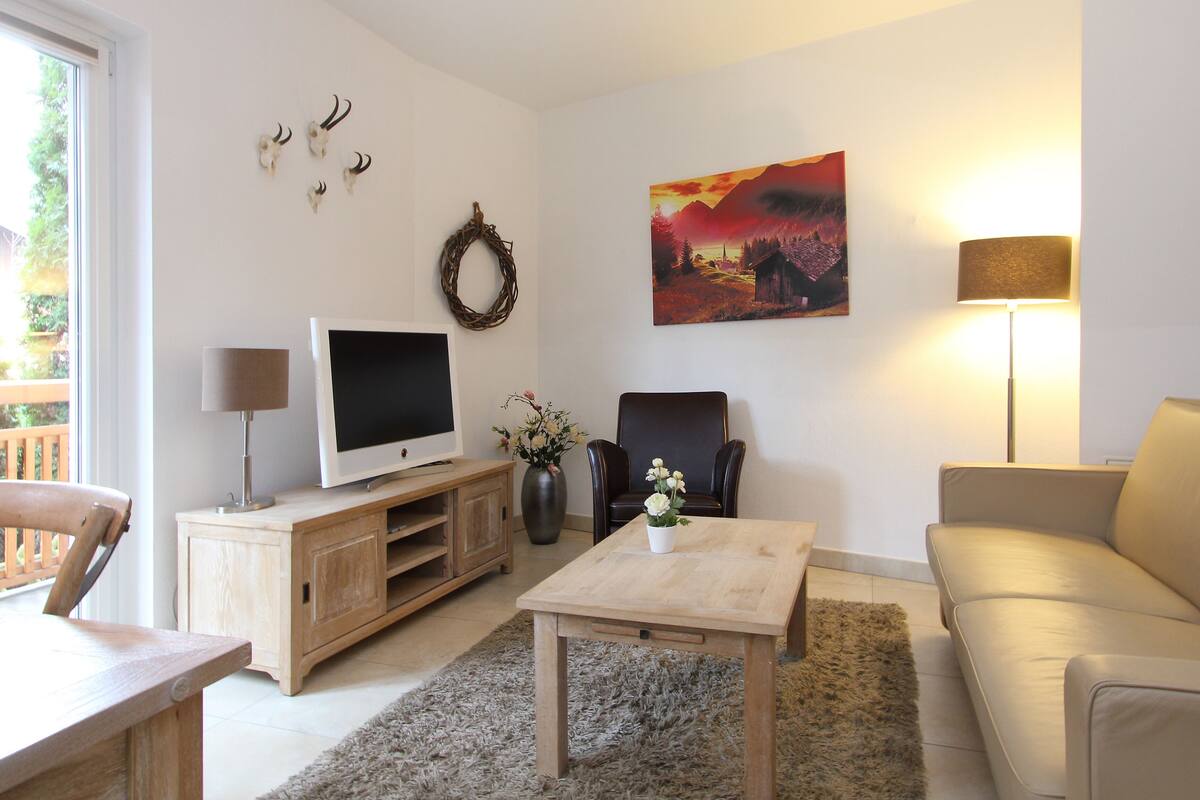 Una sala de estar con televisión, un sofá, una mesa de centro y una chimenea.