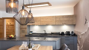 A modern kitchen with wooden cabinets, a granite countertop, and pendant lighting. - AvenidA Style Appartments by Alpin Rentals -incl Summercard (Kaprun)
