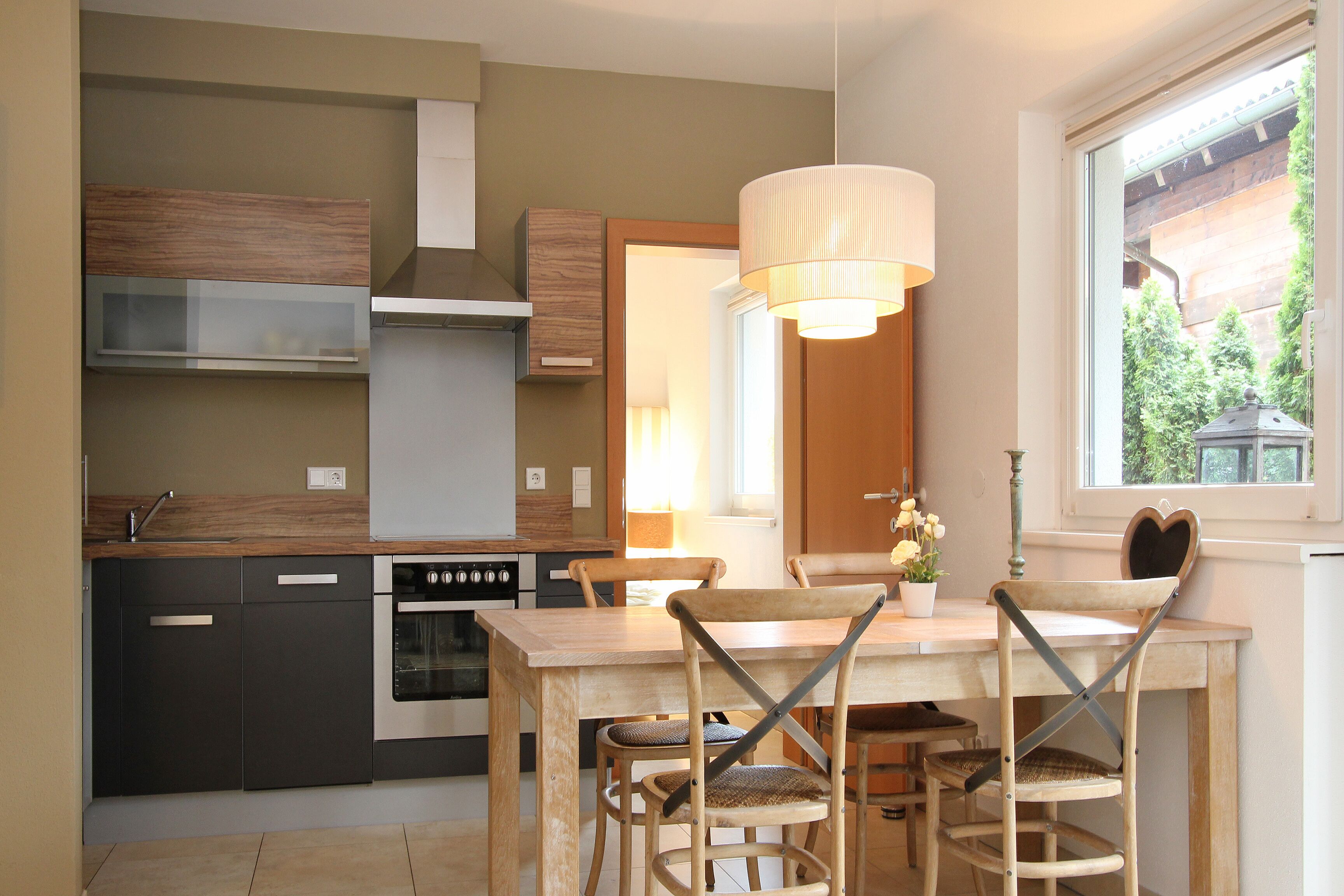 A modern kitchen with dark cabinetry, a wooden dining table, and a pendant light.