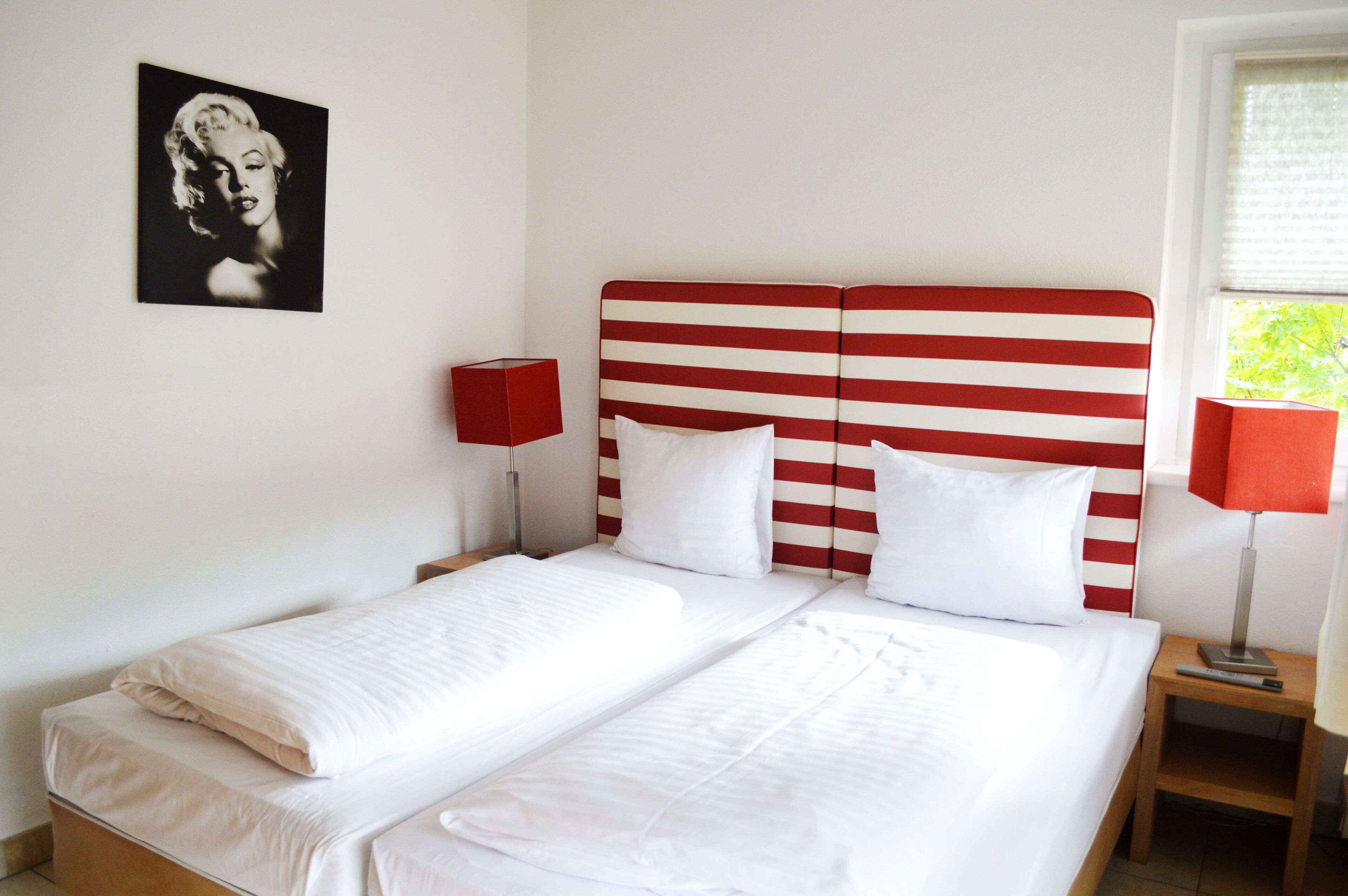 A double bed with white bedding and a red-striped headboard.