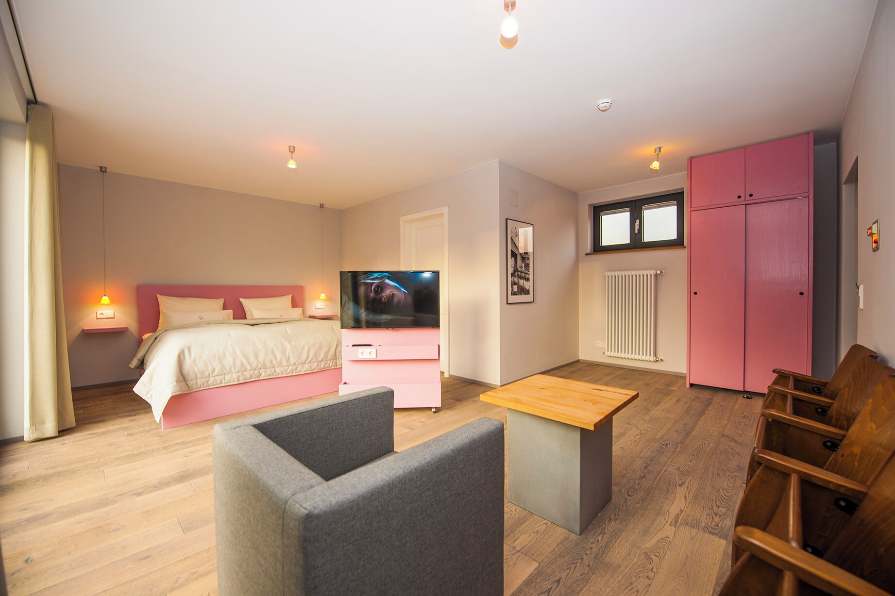 Un dormitorio con cama, mesita de noche, televisor y un armario rosa.