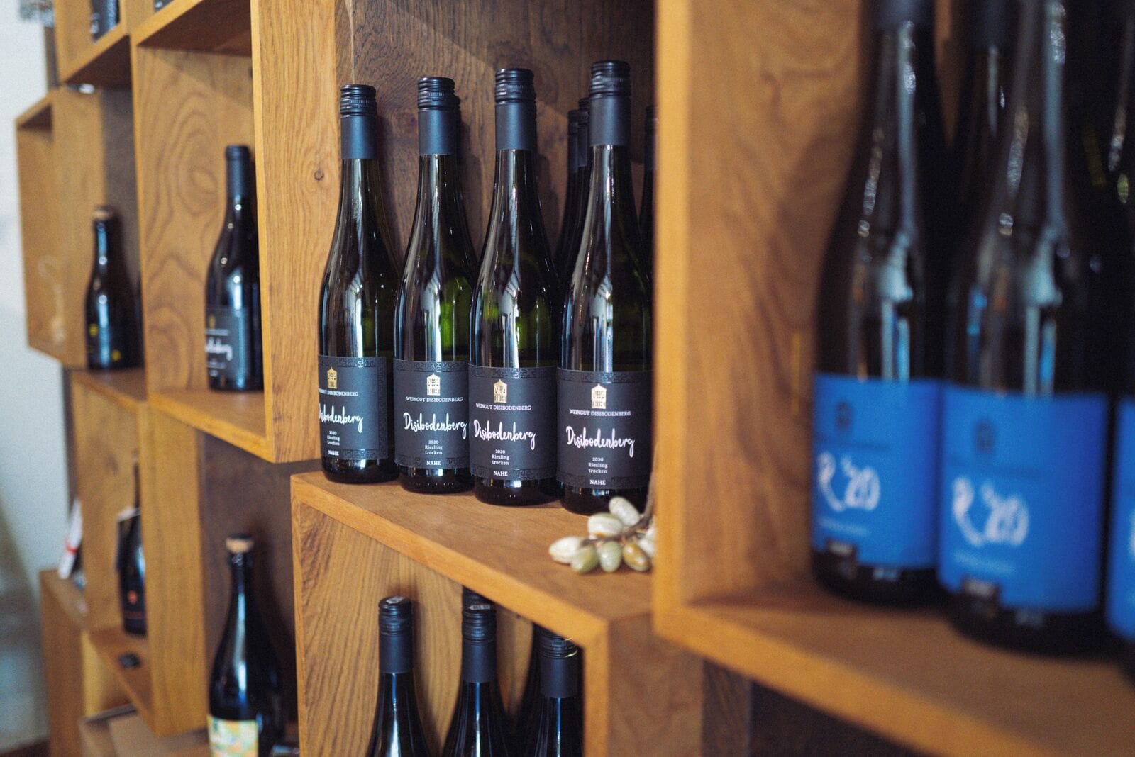 A wooden shelf with multiple wine bottles, some with labels visible.