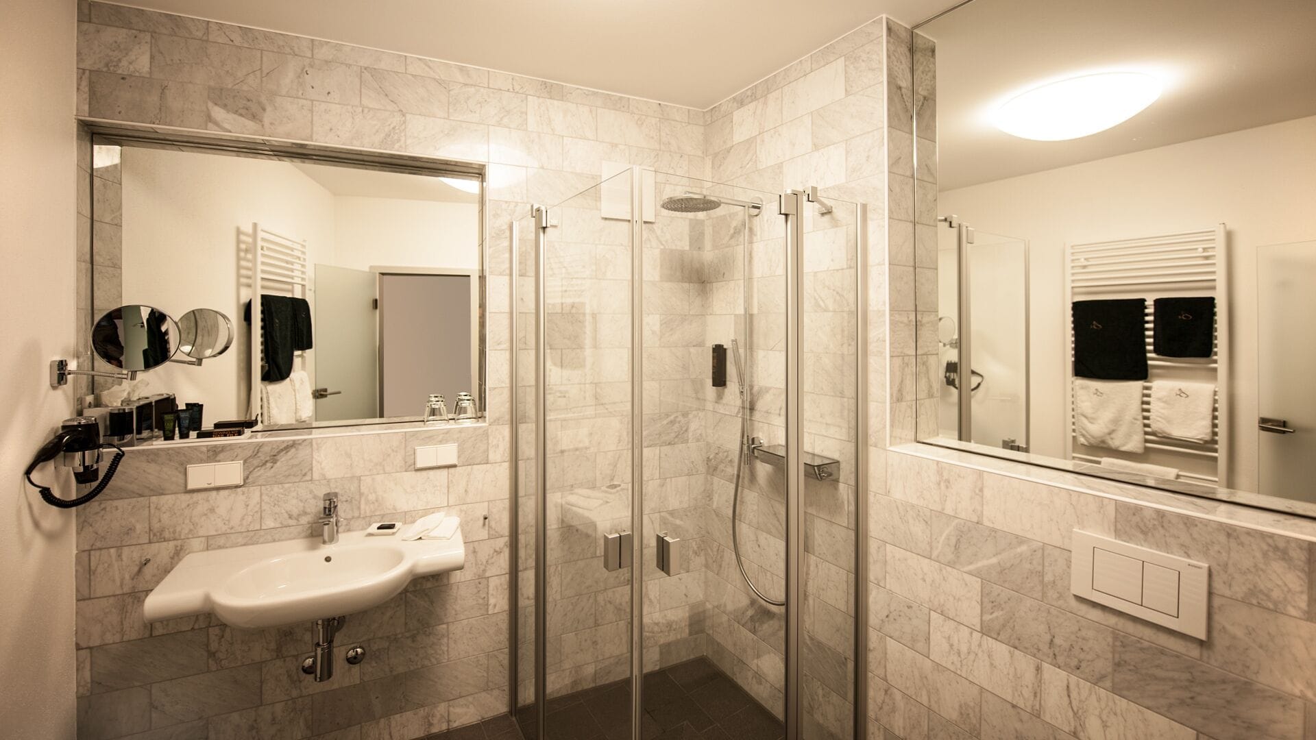 A modern bathroom with a glass-enclosed shower, a sink, and a large mirror.