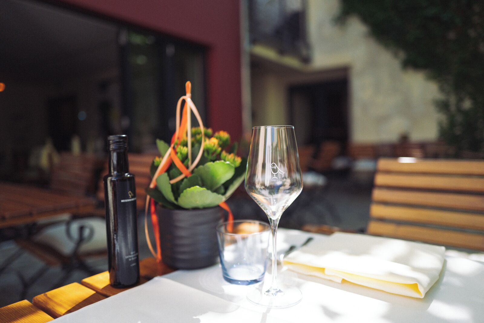 A table with a bottle, a glass, and a potted plant.