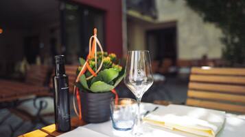 A table with a bottle, a glass, and a potted plant.