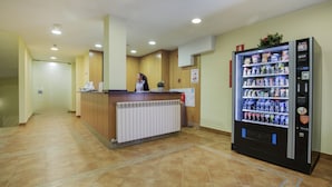 Een receptiezone met een balie, een automaat en een radiator.