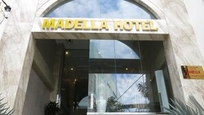 La entrada del Hotel Madella, con un cartel visible sobre la entrada y una escalera que lleva hacia él.