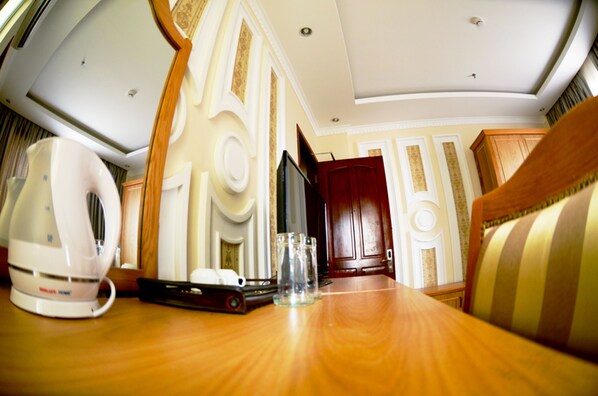 Una habitación de hotel con una mesa de madera, un televisor, una puerta roja y un sofá a rayas.