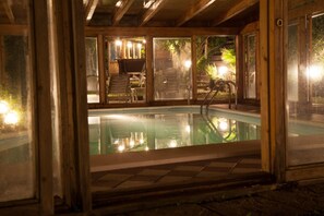 A pool area with glass doors, a chair, and a small table. - Hotel Residence Ricordo du Parc (Salsomaggiore Terme)