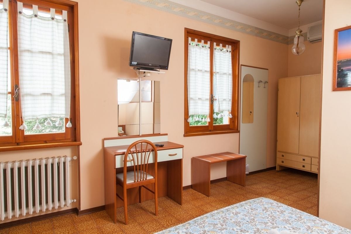 Un dormitorio con cama, escritorio, silla, televisor y armario.