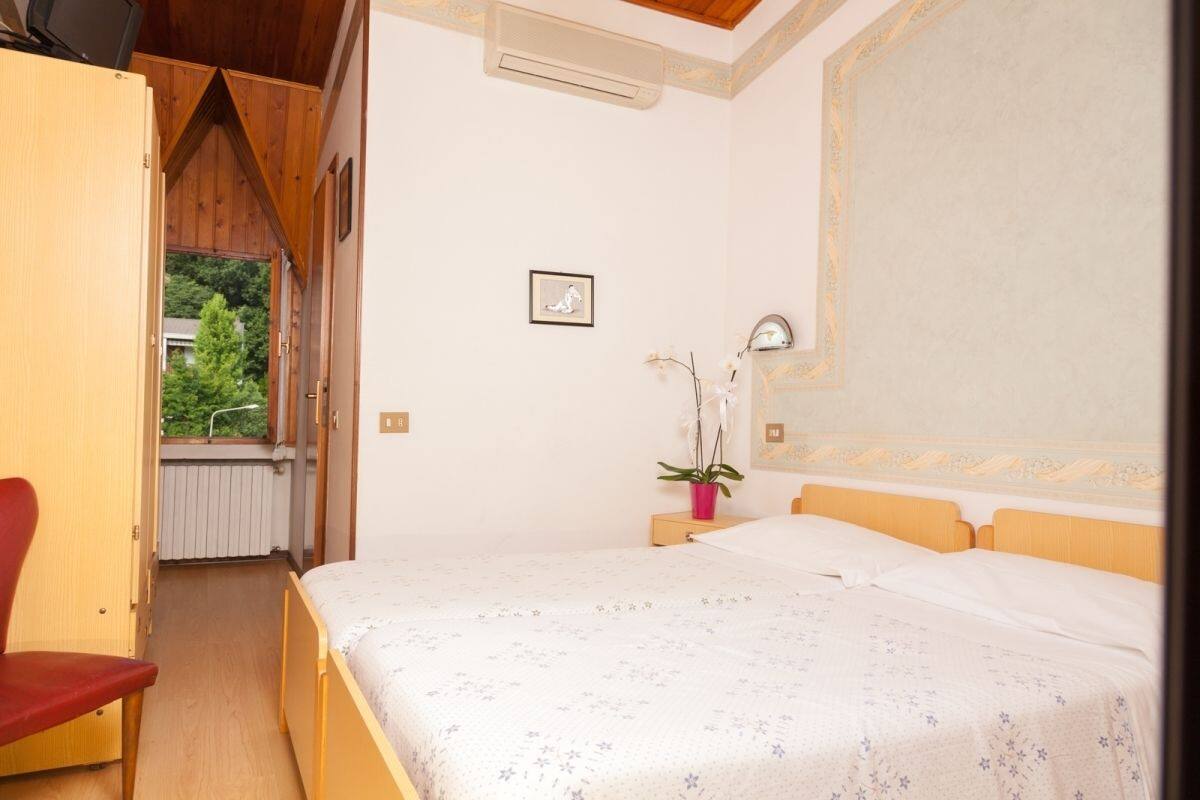Une chambre à coucher avec un lit, une chaise, une fenêtre et une plante en pot.