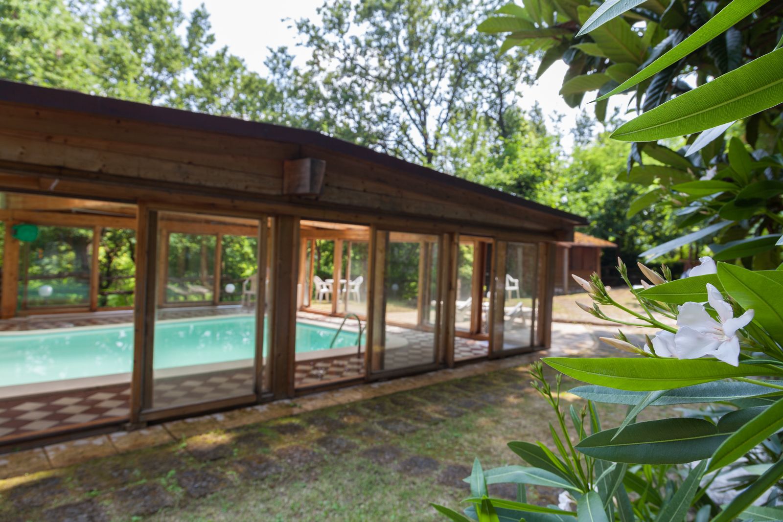 Una baita di legno con area piscina in vetro, immersa nel verde.