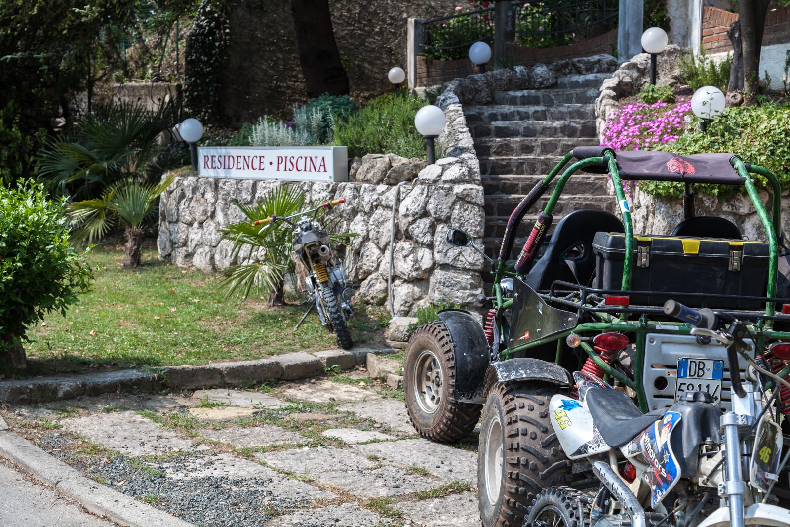 Un vehículo todoterreno robusto estacionado frente a un muro de piedra con un letrero que dice "RESIDENCE - PISCINA".