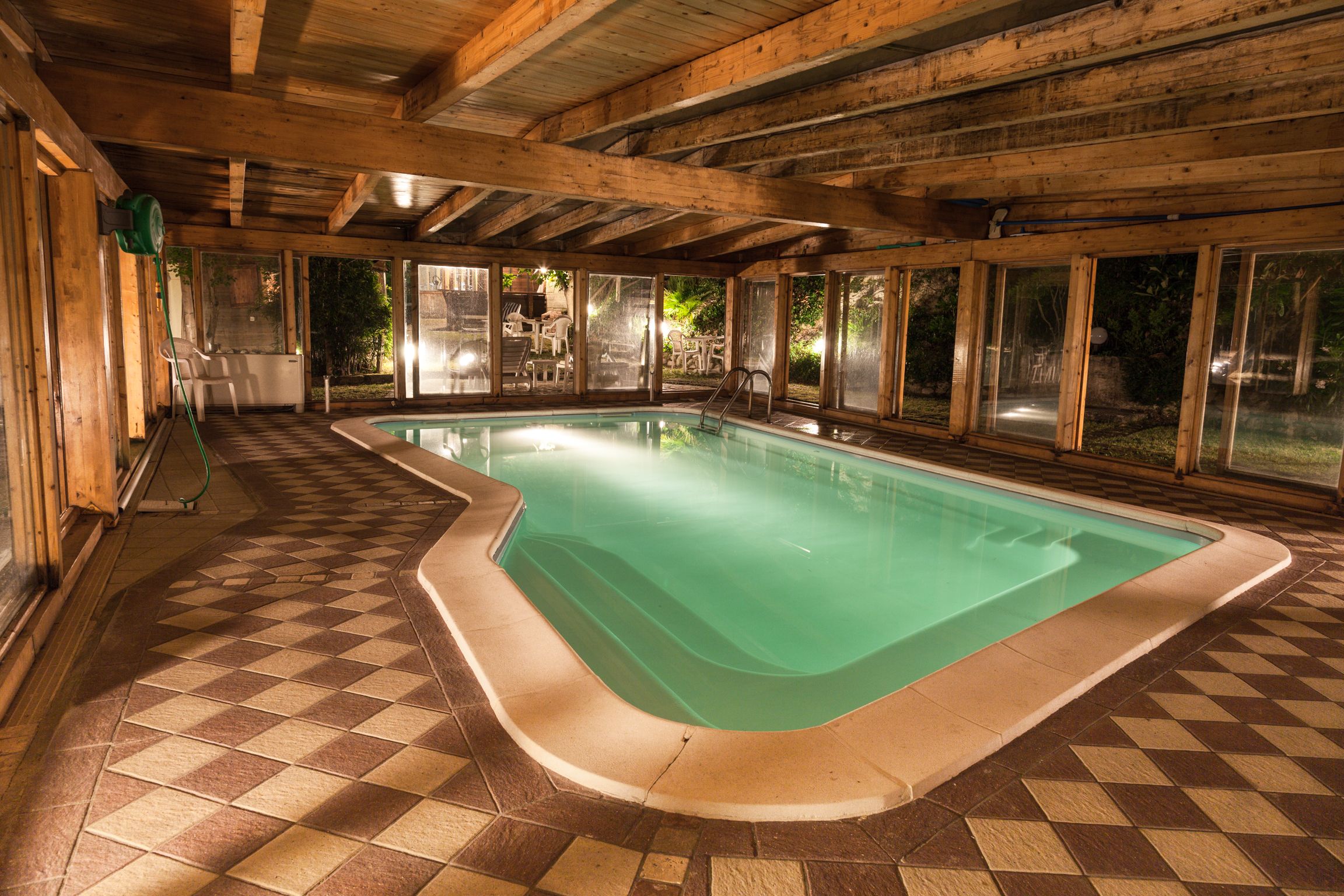A pool with a checkered floor, wooden beams, and large windows.