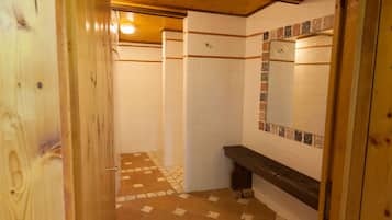 Un baño con paredes de azulejos blancos, un banco de madera y un piso de baldosas con diseño.