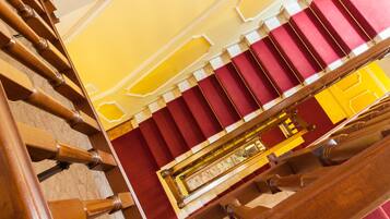 Un'imponente scalinata con una combinazione di colori rosso e giallo, che conduce a una zona con balcone e ringhiera in legno.