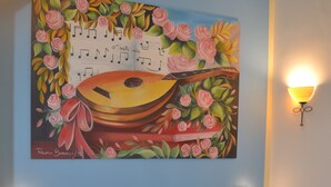 A hotel room with a bed, a painting of a guitar and roses, and two wall-mounted lamps. - Anna's Family (Naples)