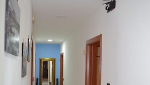 A hallway with a blue accent wall, a large mirror, and a wooden door. - Anna's Family (Naples)