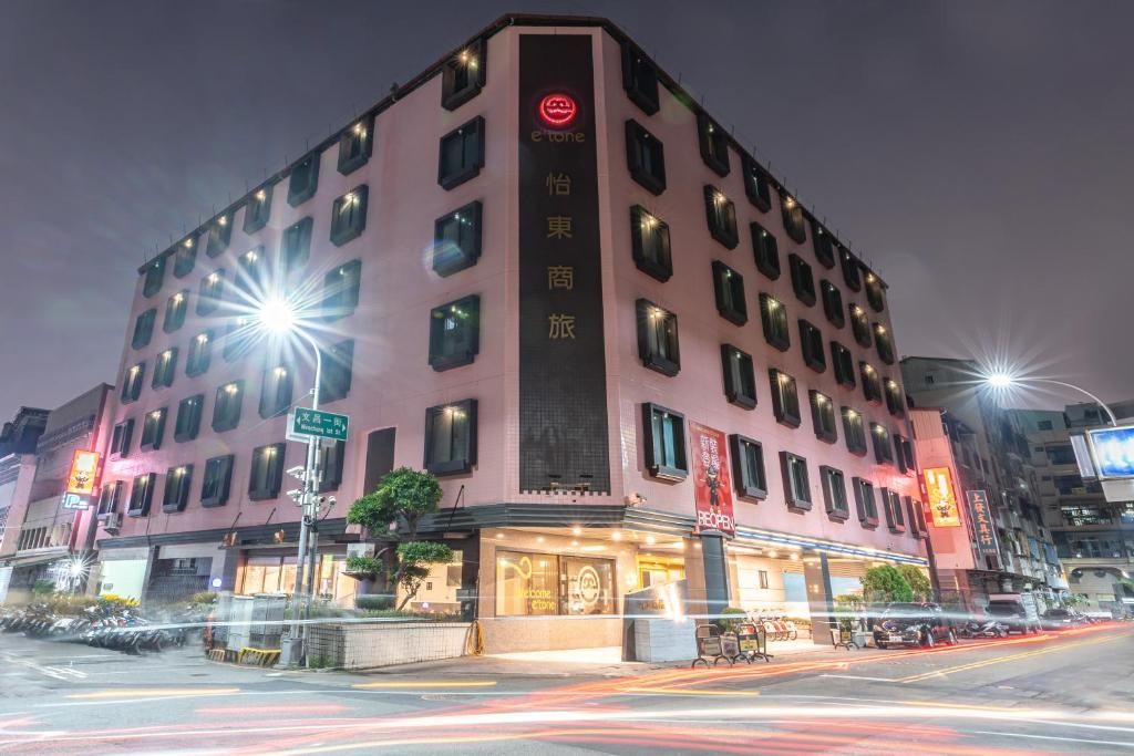 A multi-story hotel with a prominent entrance, illuminated signage, and a visible street view.