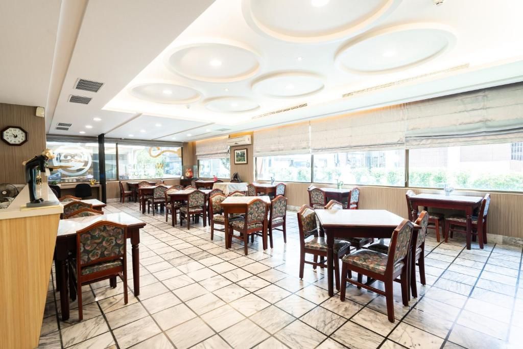 A restaurant with a tiled floor, wooden tables and chairs, and a ceiling with circular light fixtures.