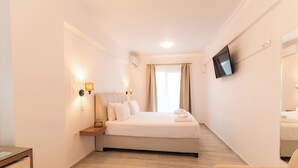A hotel room with a bed, bedside table, lamp, TV, and a chair. - Aliki Hotel (Lefkada)