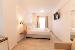 A hotel room with a bed, bedside table, lamp, TV, and a chair. - Aliki Hotel (Lefkada)
