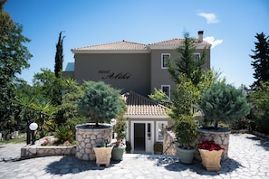 A hotel named 'Hotel Aliki' with a tiled roof, stone walls, and potted plants in the courtyard. - Aliki Hotel (Lefkada)